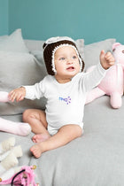 Bebé recostado usando body blanco de manga larga y gorro tejido