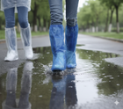 Cubrebotas plásticos impermeables azules y blancos usados bajo la lluvia