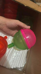 Recipiente Tutsi Pop verde y rosado sostenido en una mano