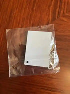 Llavero con placa metálica blanca cuadrada en bolsa transparente