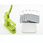 Máquina verde para chapitas de 50 mm con piezas plásticas y broches